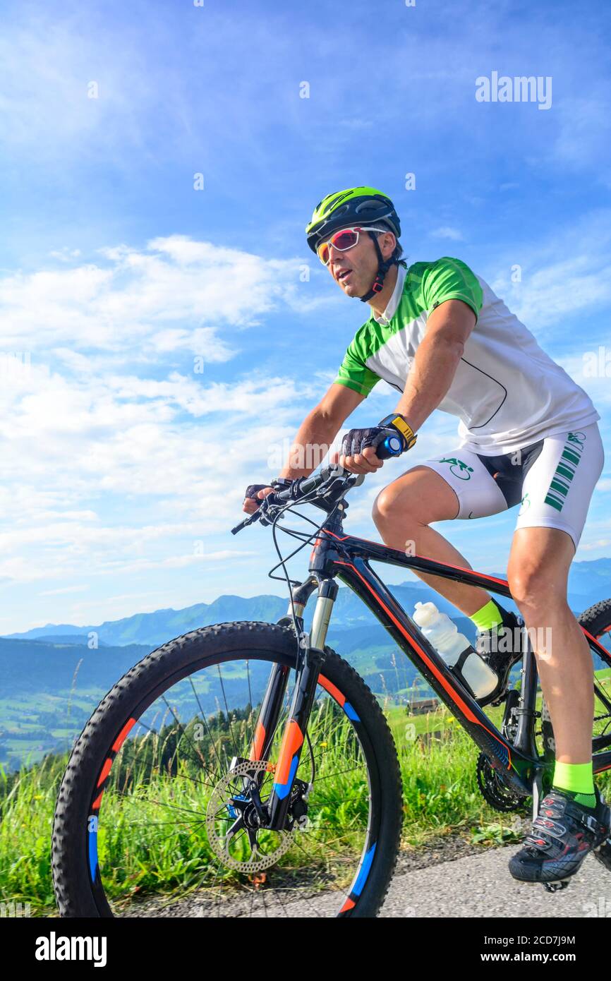 Uomo e donna in tour in mountain bike ai piedi delle colline alpine Vicino al piccolo villaggio di Sulzberg Foto Stock