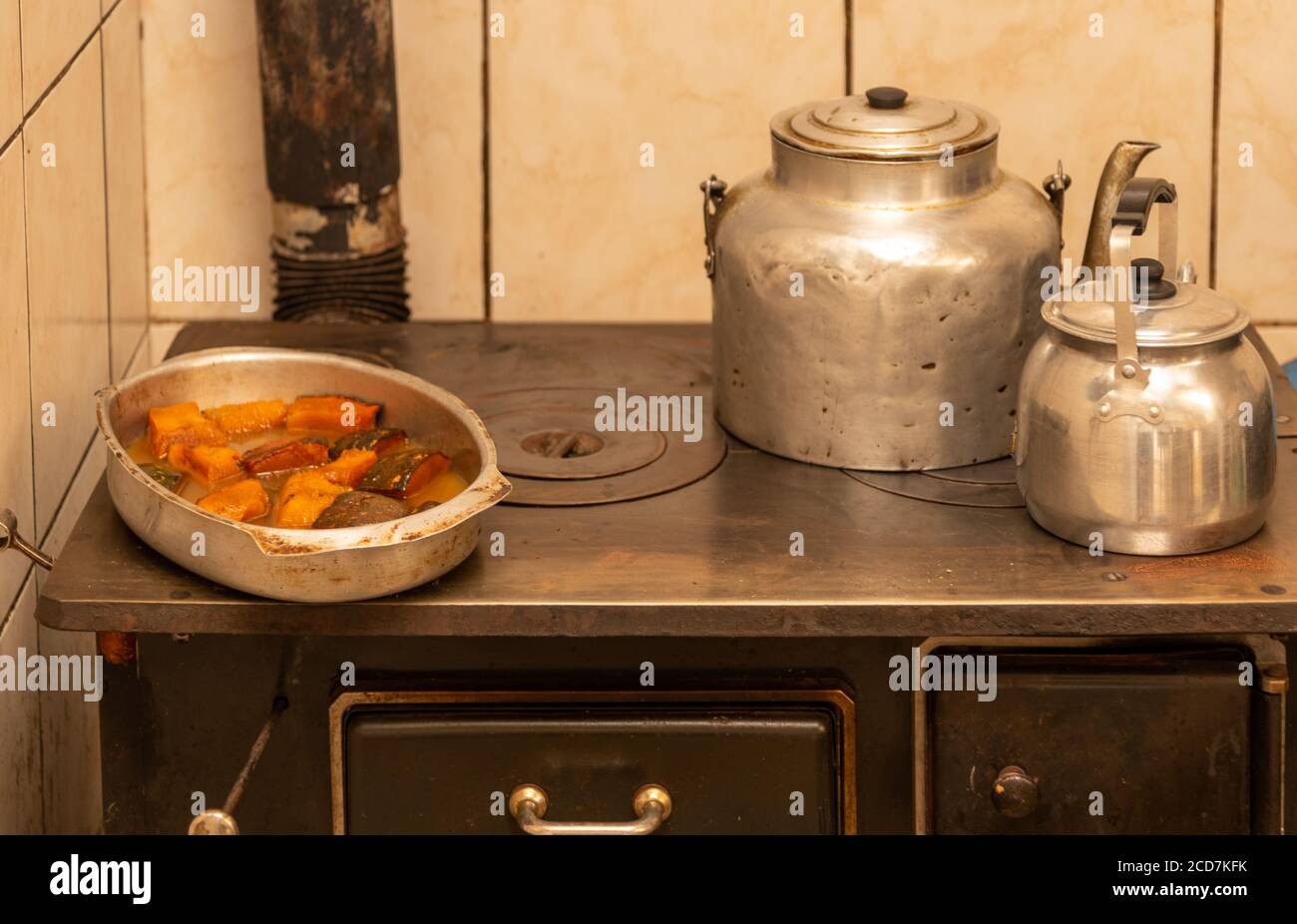 Vista su una stufa a legna con due bollitori e un vassoio in metallo riempito di zucca zuccherata e caramellata. Preparazione del pranzo giornaliero. Cucina brasiliana Foto Stock