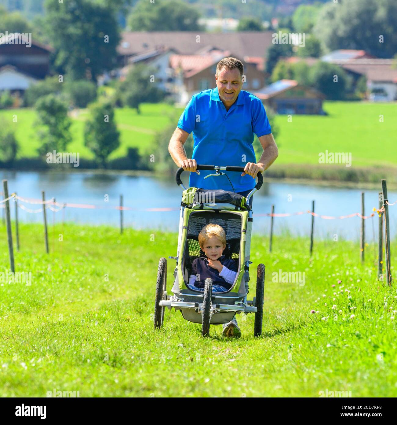 Uomo che fa una sessione di jogging con un figlio in buggy in un bellissimo paesaggio Foto Stock