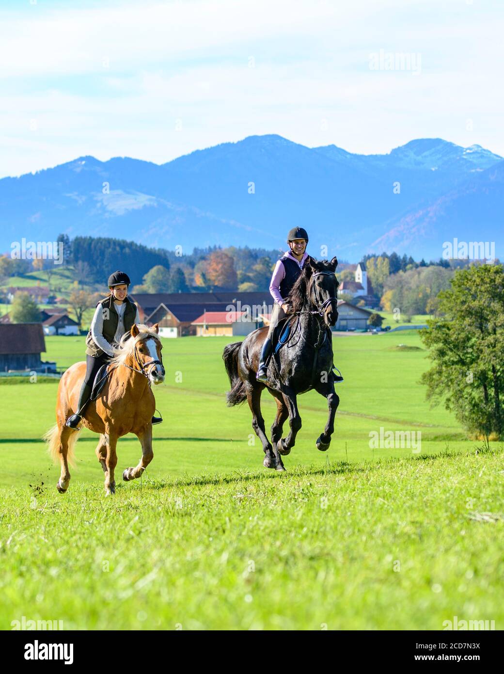 Due donne sportivo in sella ai loro cavalli sul prato in Algovia bavarese Foto Stock