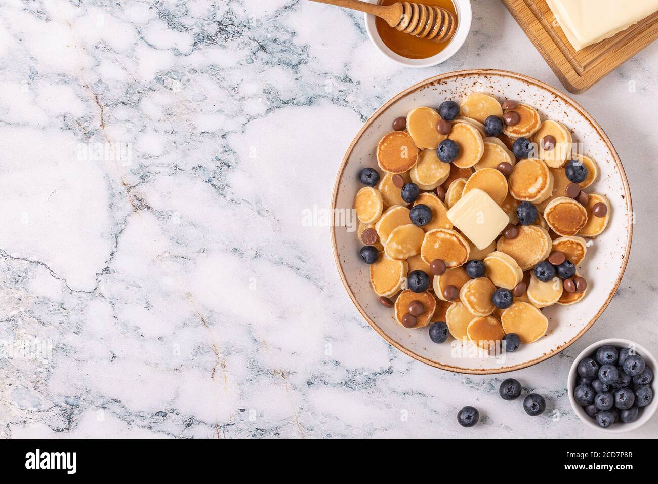 Colazione alla moda con mini pancake, mirtilli e patatine al cioccolato, vista dall'alto. Foto Stock