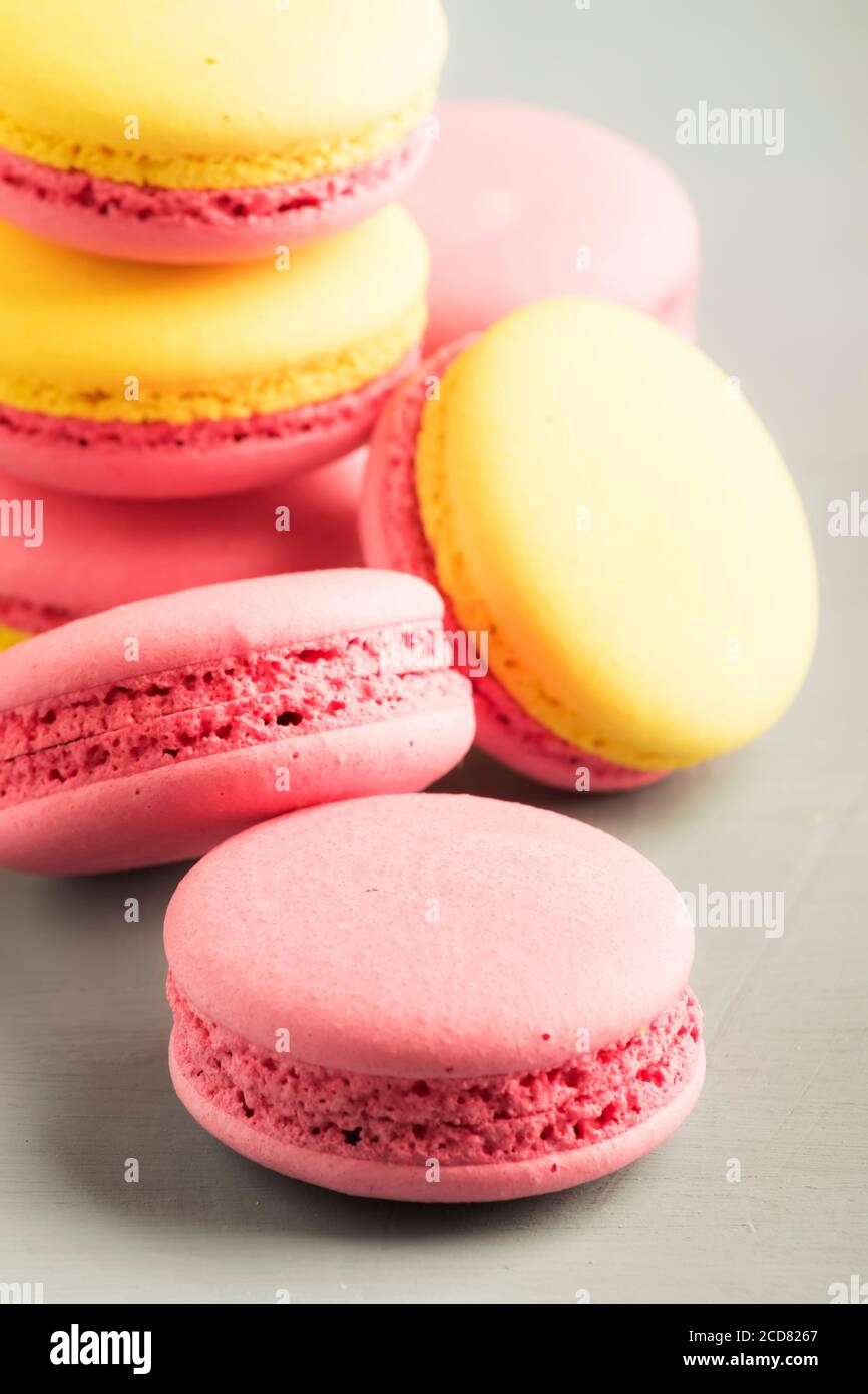 Macaroon giallo rosa torte su sfondo grigio tavolo, posto per il testo, stile minimalismo alla moda, fuoco selettivo Foto Stock