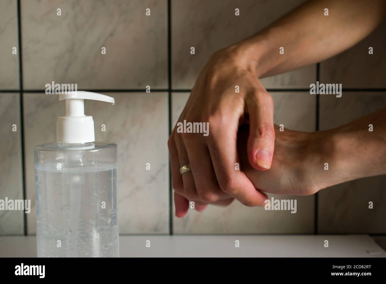 Primo piano delle mani femminili applicazione di gel igienizzante liquido sfregamento mani pulizia personale prevenzione igiene a casa. Flacone igienizzante. Foto Stock