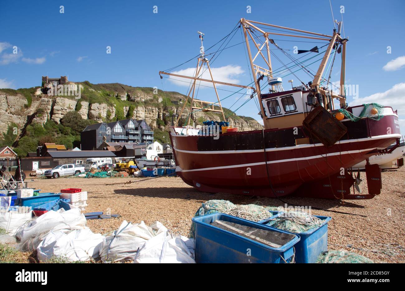 Barche da pesca sulla spiaggia di ciottoli del porto di Hastings, la più grande flotta peschereccia lanciata a terra in Europa, con la collina orientale sullo sfondo. Foto Stock