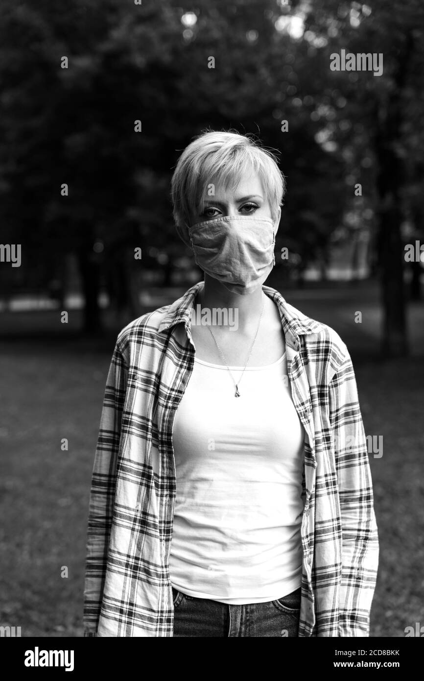 giovane donna bionda in una maschera protettiva. mezzo di protezione individuale. epidemia di coronavirus. immagine monocromatica Foto Stock