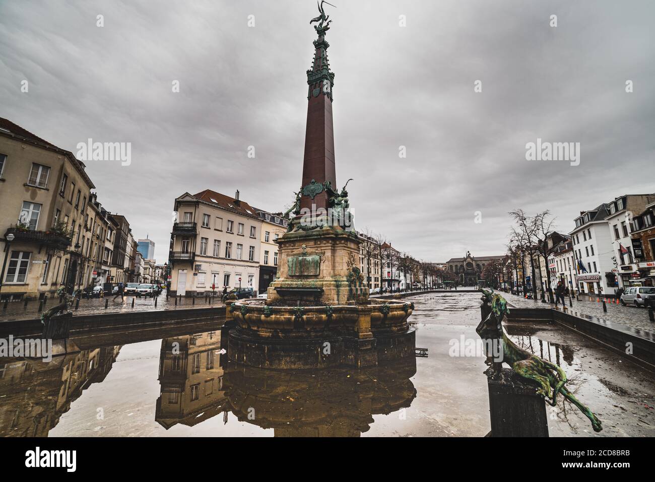 Eclettica architettura riflessione nella fontana Fontaine Anspach in Quai Aux Briques contro un clima cupo in Place de Brouckere - Bruxelles Foto Stock