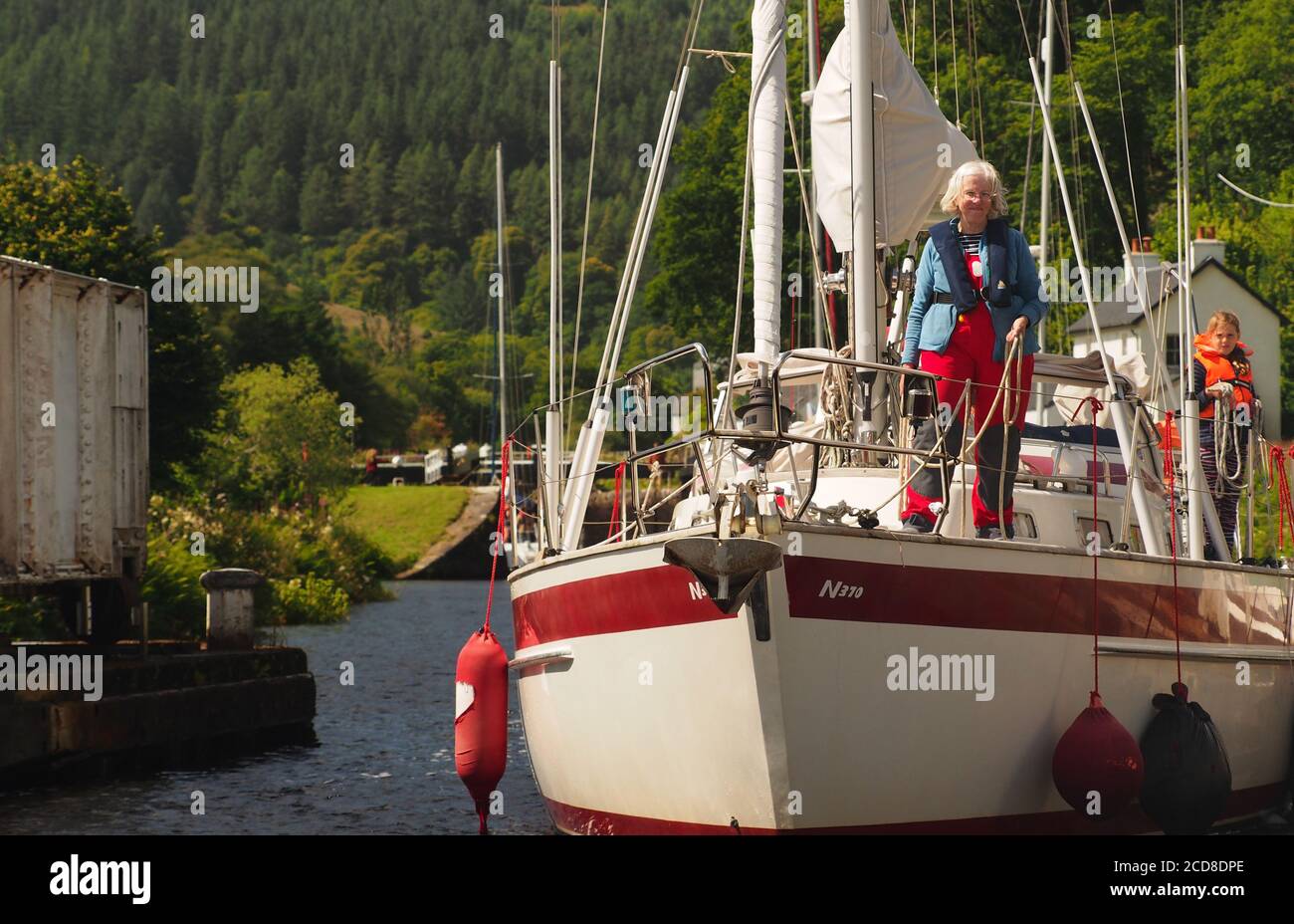 Yacht tra le serrature cinque e sei a Cairnbaan, Crinan Canal, Argyll, Scozia con una donna anziana e una ragazza a bordo Foto Stock