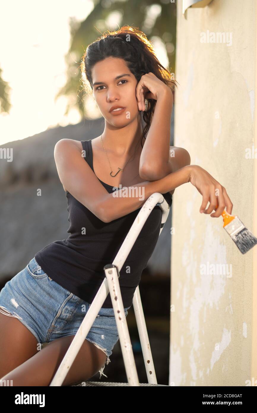 Giovane donna che prende una pausa dalla pittura di un muro Foto Stock