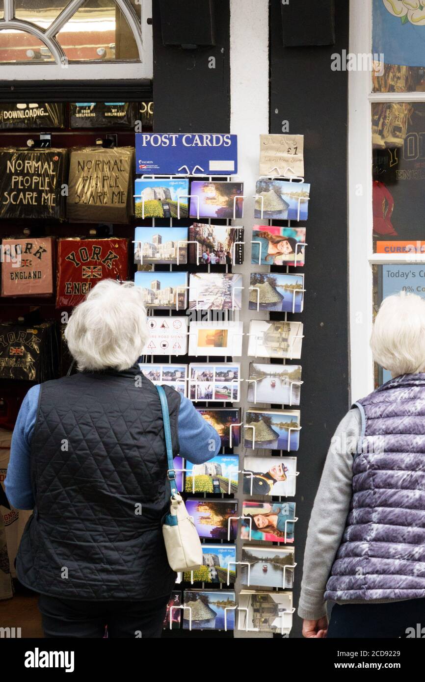 Rack di cartoline postate all'esterno di un negozio visto da un turista più anziano, York, North Yorkshire, Inghilterra, Regno Unito. Foto Stock