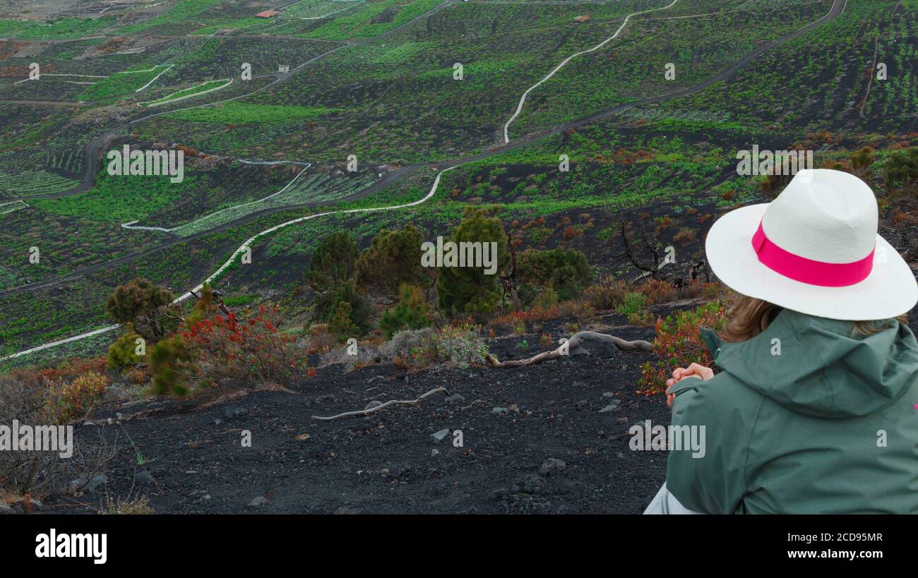 Spagna, Isole Canarie, la Palma, escursionista seduto sul bordo della strada, di fronte a un paesaggio vulcanico Foto Stock