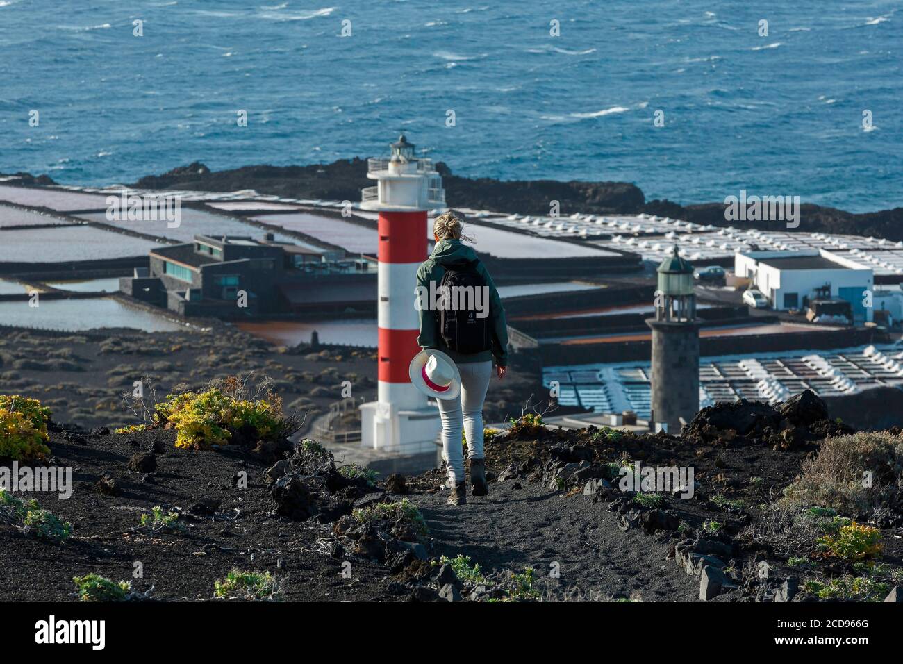 Spagna, Isole Canarie, la Palma, escursionista su un sentiero sul mare, vicino a un faro circondato da sale Foto Stock