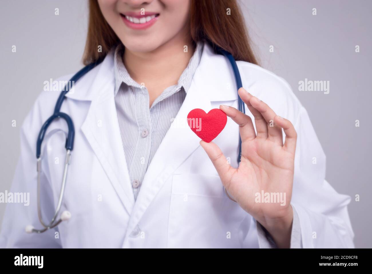 Concetto sano : giovane medico asiatico con cuore rosso in mano, volto anonimo Foto Stock