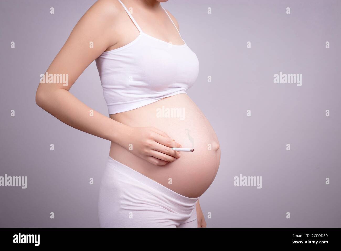 Concetto sano incinta. Donna incinta con sigaretta in mano. Foto Stock
