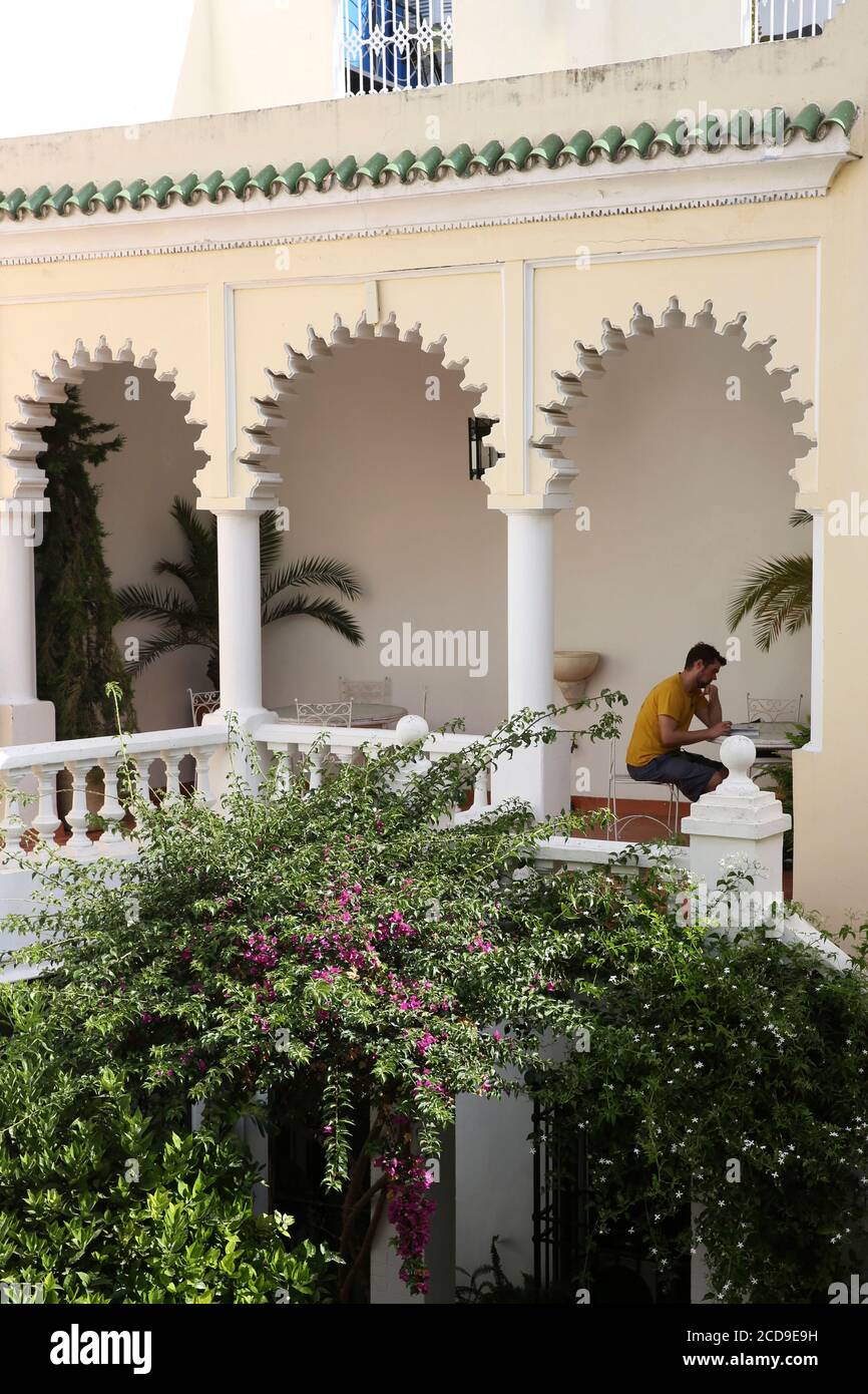 Marocco, Tangeri Tetouan regione, Tangeri, uomo seduto nel patio della legazione americana invaso da bougainvillea Foto Stock