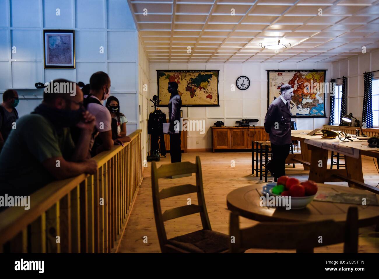 I visitatori guardano a una scena ricostruita del tentativo di assassinio con l'immagine di Hitler raffigurata nella parte storica di Wolf's Lair, il primo quartier generale militare di Hitler sul fronte orientale con l'obiettivo di iniziare l'Unione Sovietica, A Gierloz. Il famoso Wolf's Lair era uno dei quartieri generali segreti più importanti della Germania nazista situata oggi nella Polonia orientale. Il sito nazista è famoso per il tentativo di assassinio della vita Hitler di Adolf, nota come operazione Valkyrie, Claus von Stauffenberg e altri che hanno preso di mira Hitler con una bomba a valigia durante un incontro all'interno del Lair di Wolf. Foto Stock