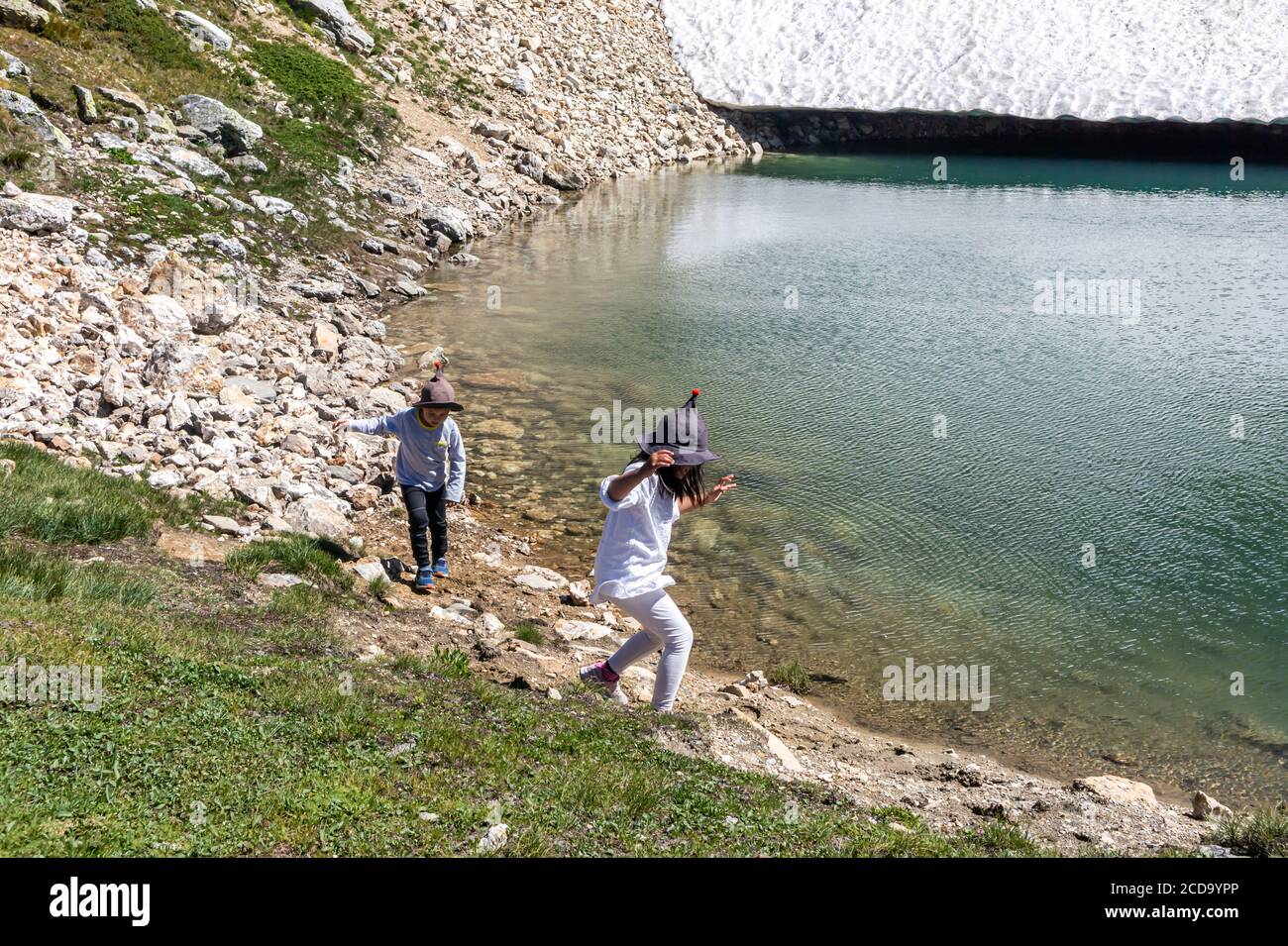 Due bambini asiatici che corrono e giocano in montagna, lago e ghiacciaio in estate. Un ragazzo e una ragazza che si divertono nei giorni festivi ad Aosta, in Italia. Foto Stock