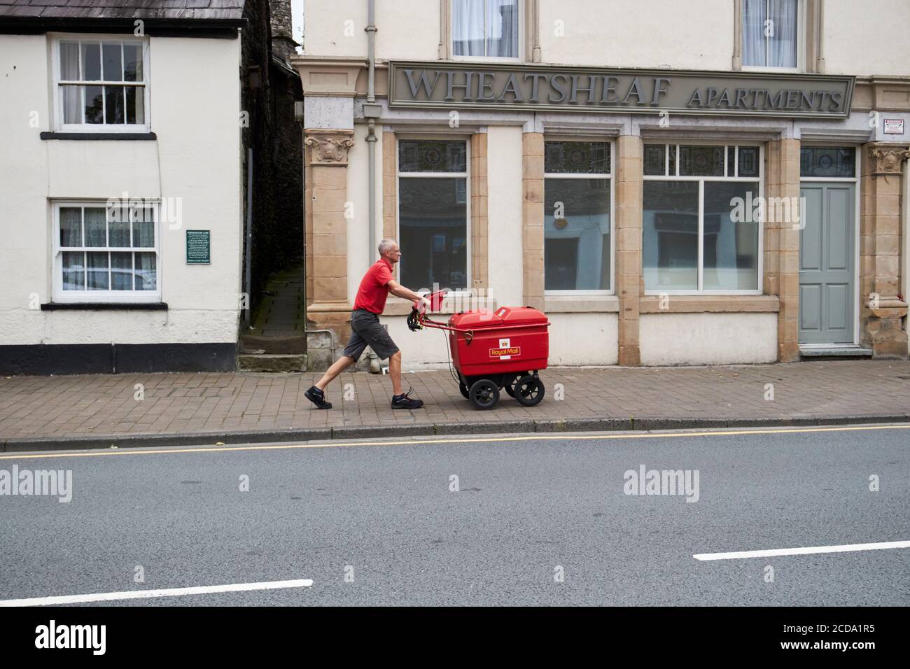 Postino che spinge in salita lungo highgate Kendal cumbria england regno unito Foto Stock