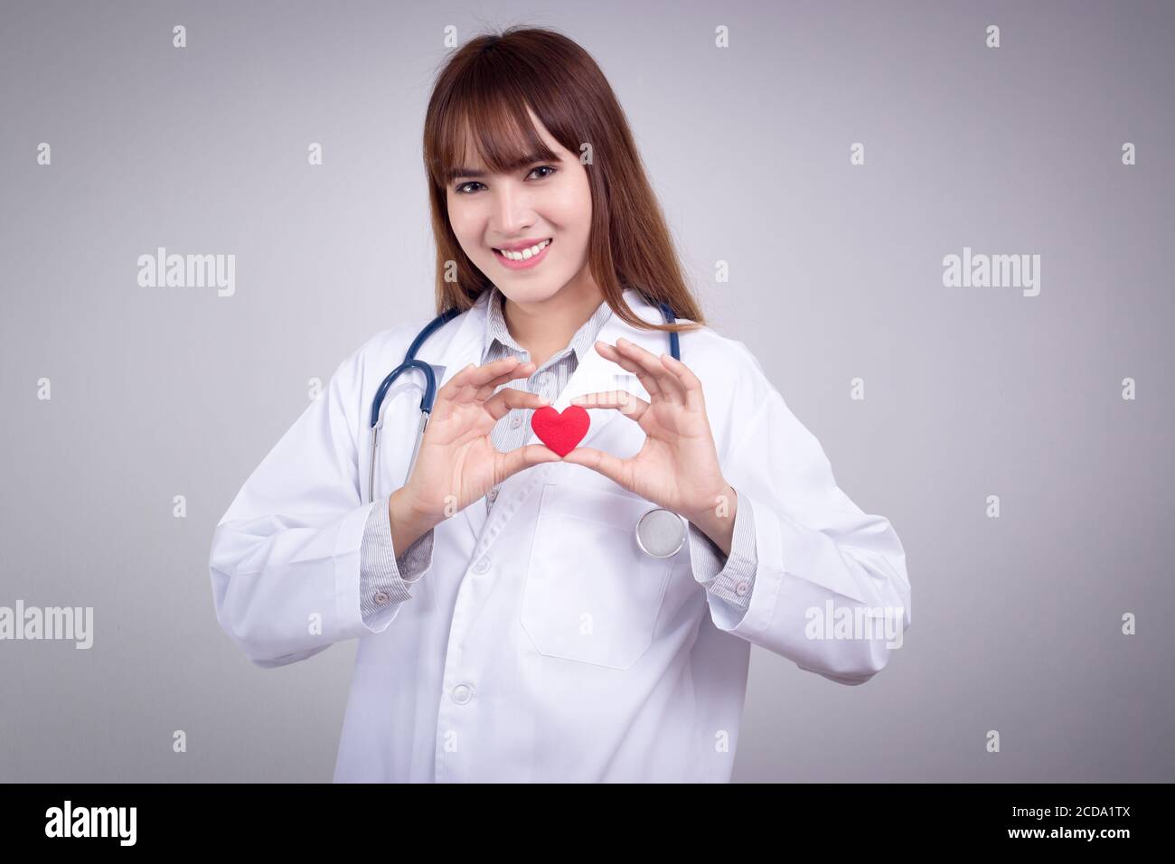 Concetto sano : giovane medico asiatico con cuore rosso in mano Foto Stock