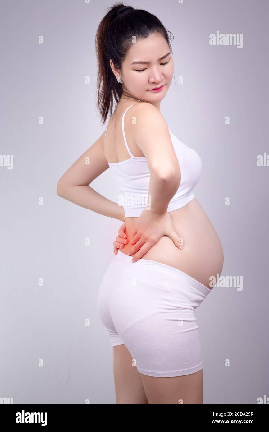 Concetto di problema sano incinta : giovane donna asiatica incinta con un forte dolore massaggiante il suo mal di schiena - dolore in rosso Foto Stock