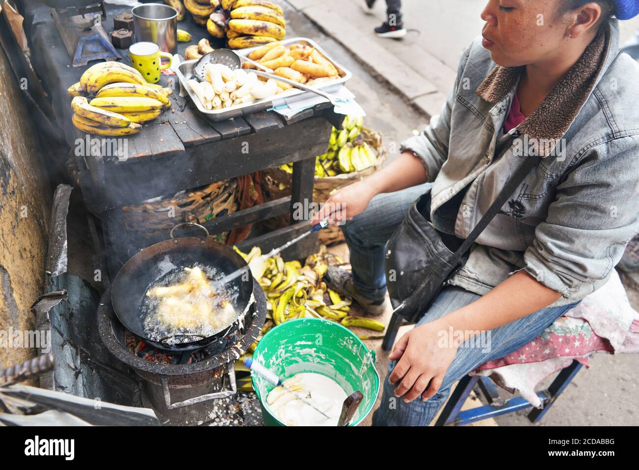 Antananarivo, Madagascar - 24 aprile 2019: Donna malgascia locale friggere le banane nel petrolio al suo stallo sul mercato accanto alla strada principale. Cibo fresco preparato su Foto Stock