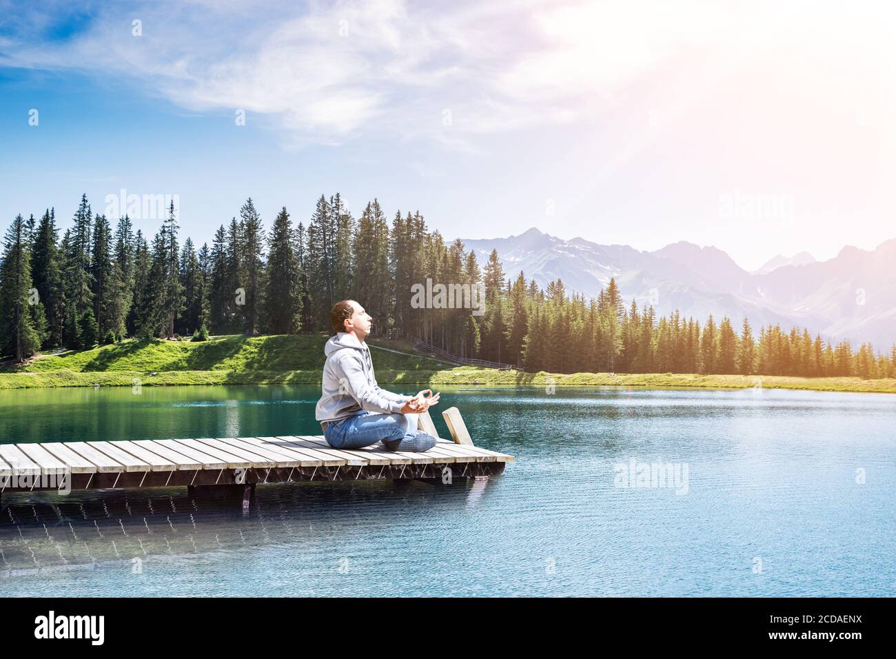 Esercitazione di energia di meditazione dell'uomo giovane vicino al lago dell'acqua Foto Stock