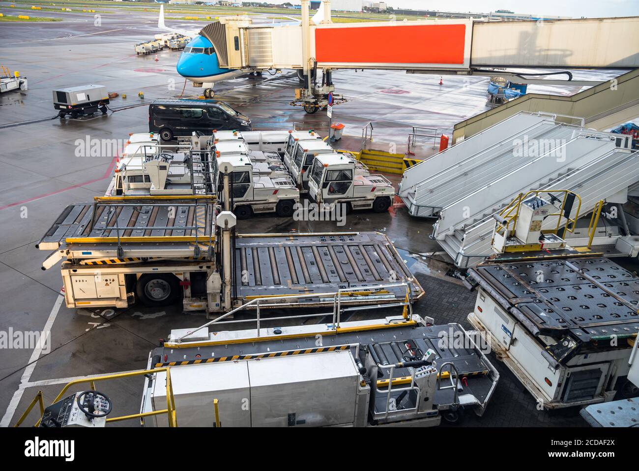 Carrelli per bagagli e altre attrezzature per il carico e lo scarico di aeromobili sulla asfalto di un aeroporto Foto Stock