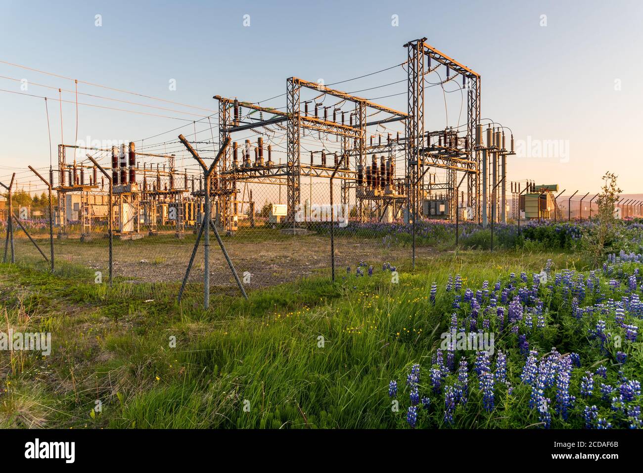 Sottostazione elettrica recintata in campagna al tramonto Foto Stock