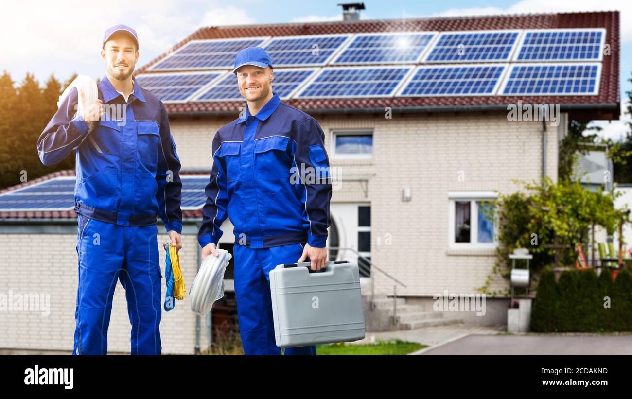 Sorridenti tecnici addetti alla riparazione di elettricisti di fronte alla casa Foto Stock