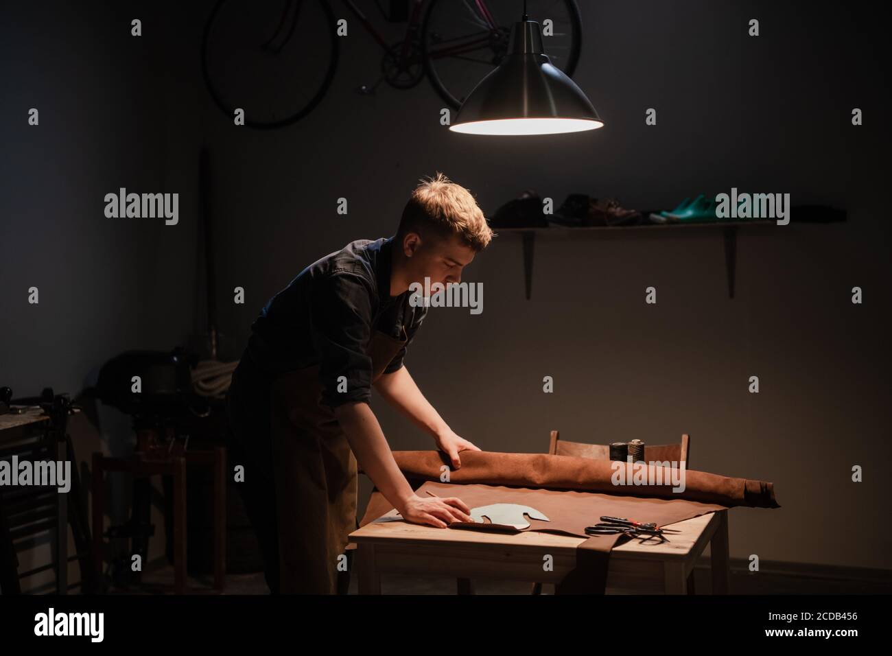 un giovane è impegnato nel mestiere di famiglia di realizzazione di scarpe in pelle in officina Foto Stock
