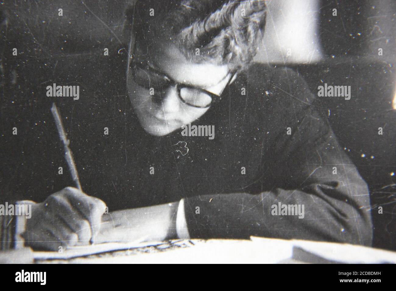 Bella fotografia in bianco e nero degli anni '70 di un giovane studioso che lavora ai suoi studi. Foto Stock