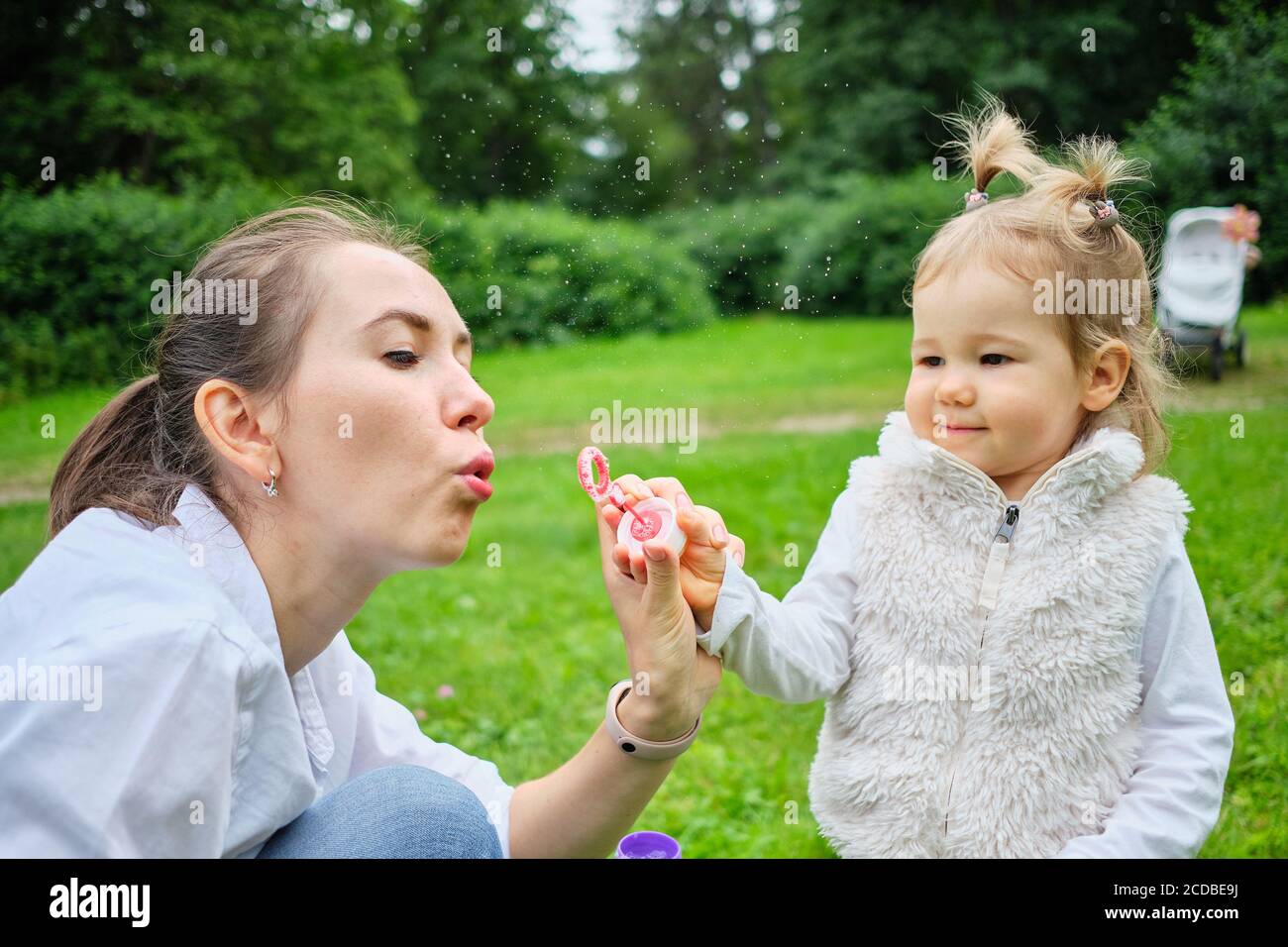 Il bambino felice con la mamma soffia le bolle di sapone. Foto Stock