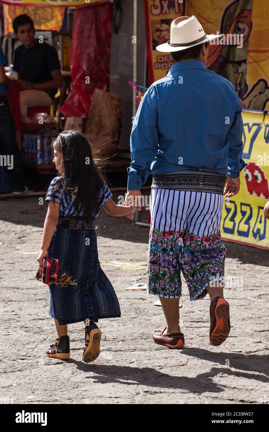 Un padre e una figlia Tzutujil in abito tradizionale a piedi nel mercato aperto settimanale a Santiago Atitlan, Guatemala. Foto Stock