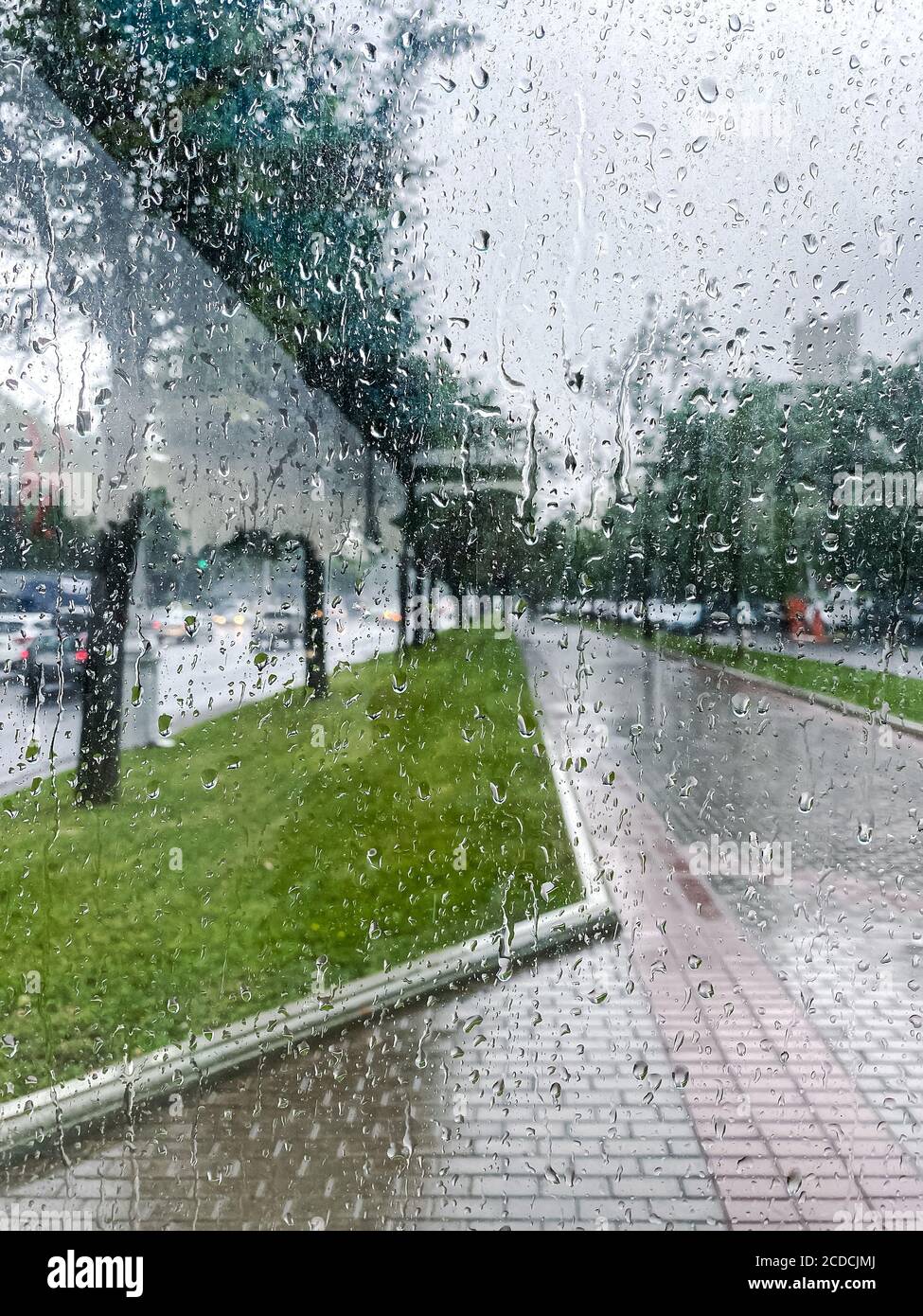 pioggia acqua su vetro finestra con sfocato sfondo della strada della città Foto Stock