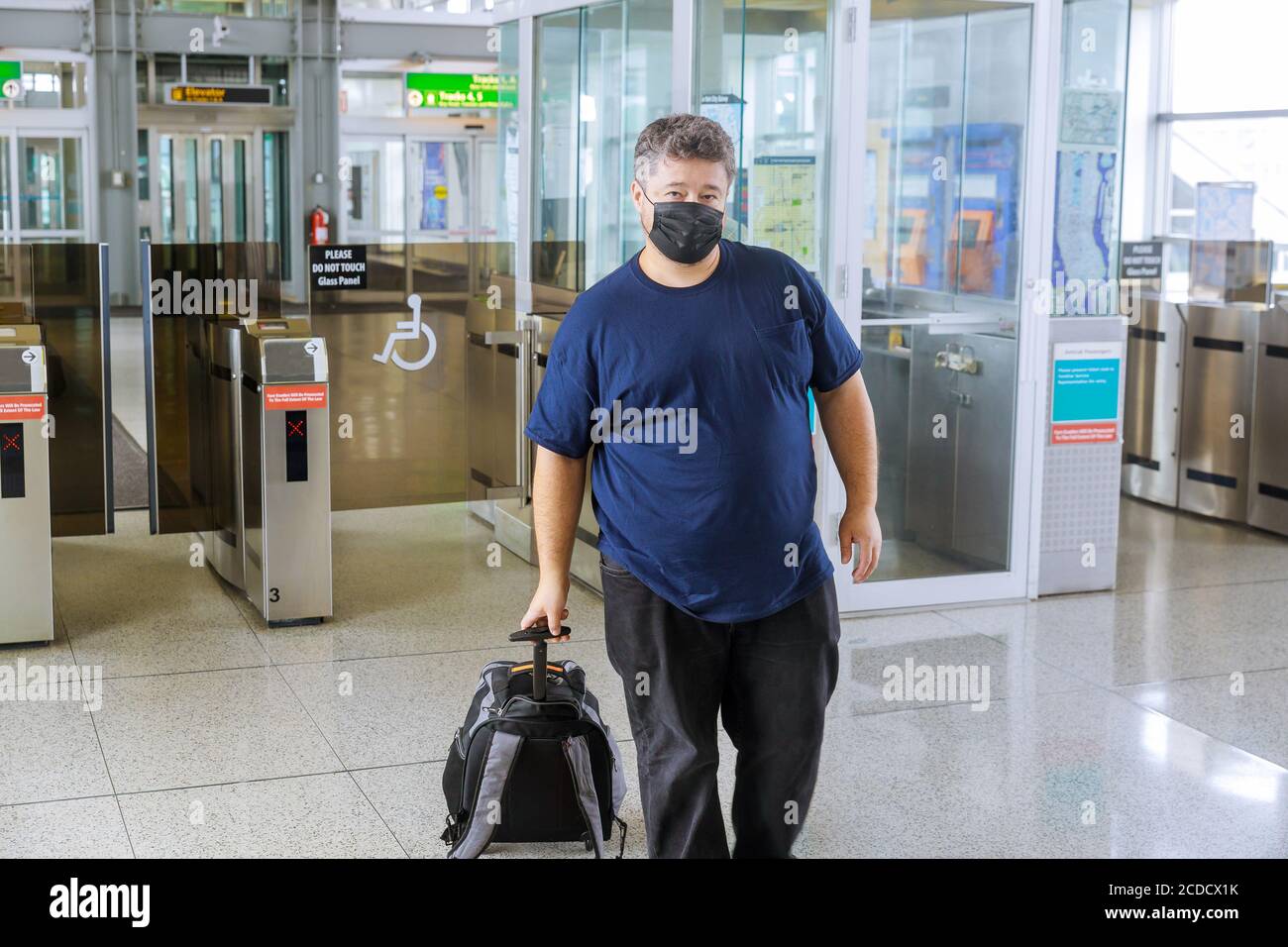 Il viaggiatore uomo con valigia sulle ruote indossa una maschera protettiva durante Pandemia focolaio di afraids di influenza pericolosa coronavirus COVID-19 pone a. piattaforma Foto Stock
