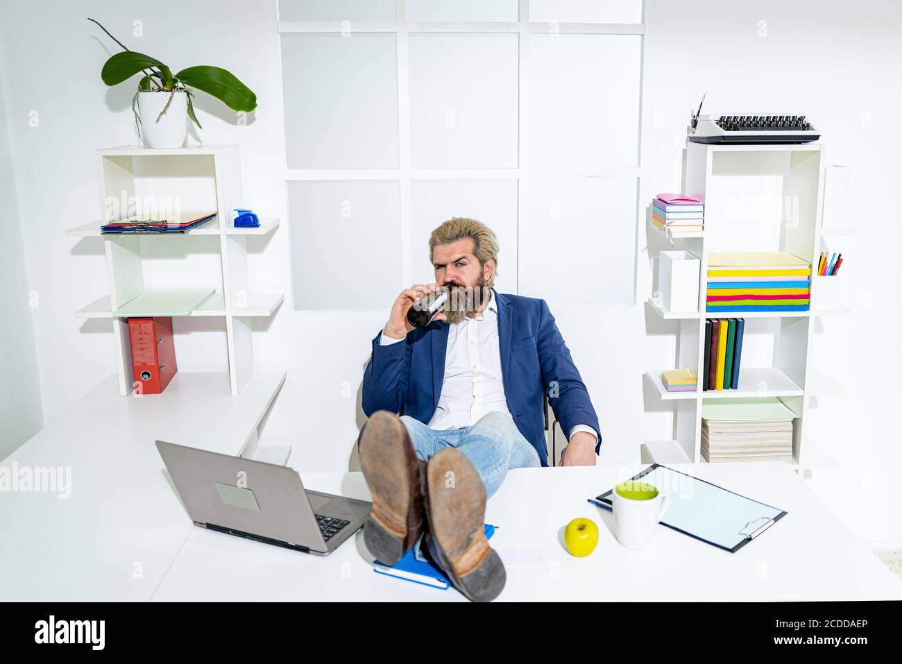 Hipster freelance, lavoratore d'ufficio, uomo d'affari che finiscono il lavoro prima della scadenza, ubriaco fine della giornata lavorativa. Un uomo d'affari ubriaco in ufficio. Foto Stock