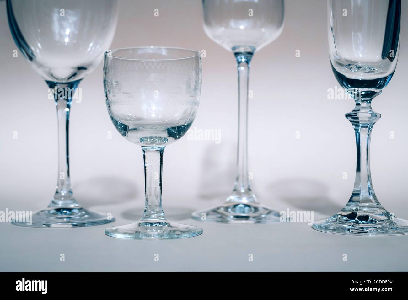 Bicchieri di vino su un tavolo soleggiato gettano ombre, luce del sole, cristalleria, bicchieri di vino, flauto champagne. Foto Stock