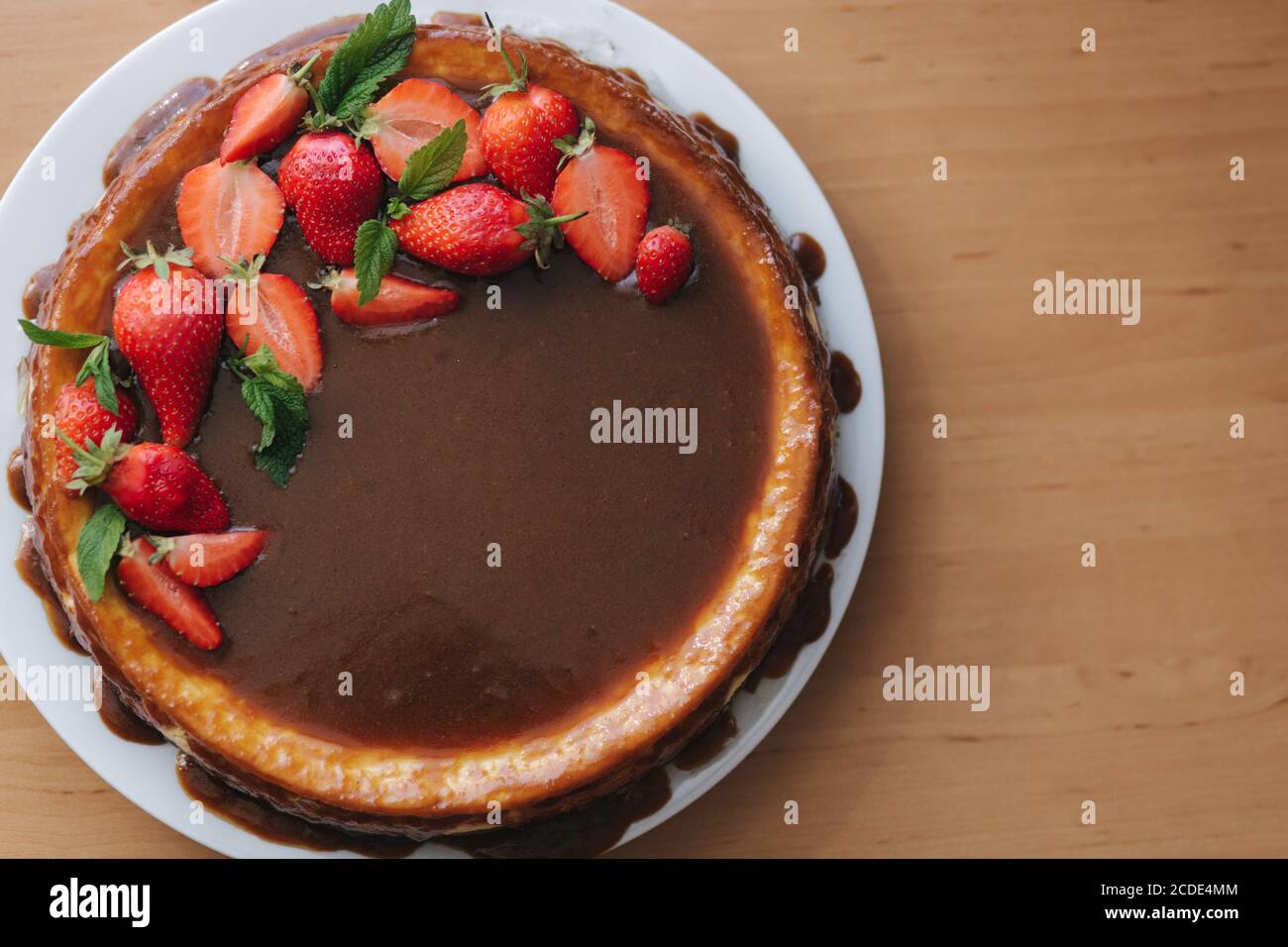 Gustosa crostata di fragole decorata con foglie di menta su tavolo di legno. Smalto al caramello sulla crostata. Colazione vegana. Senza lattosio e glutine. Vista dall'alto Foto Stock
