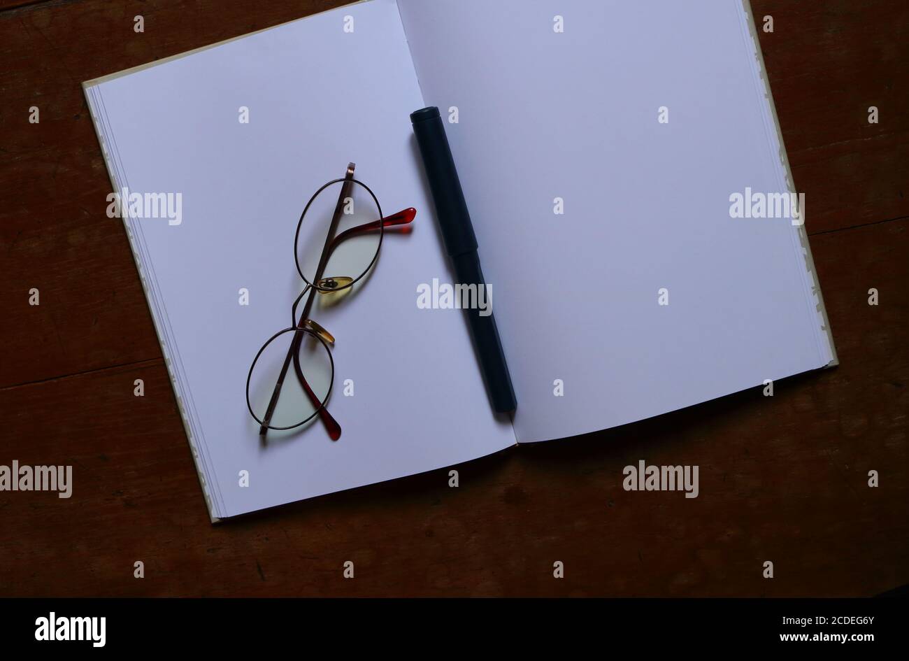 Closeup taccuino vuoto, occhiali e penna messo su tavolo di legno Foto Stock