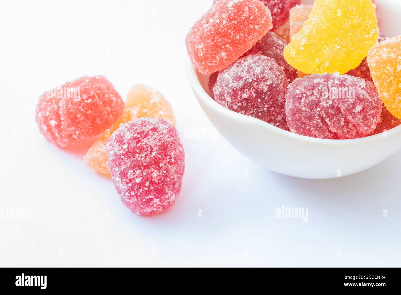 Caramelle di gelatina in ciotola bianca su uno sfondo bianco e. vicino al recipiente Foto Stock