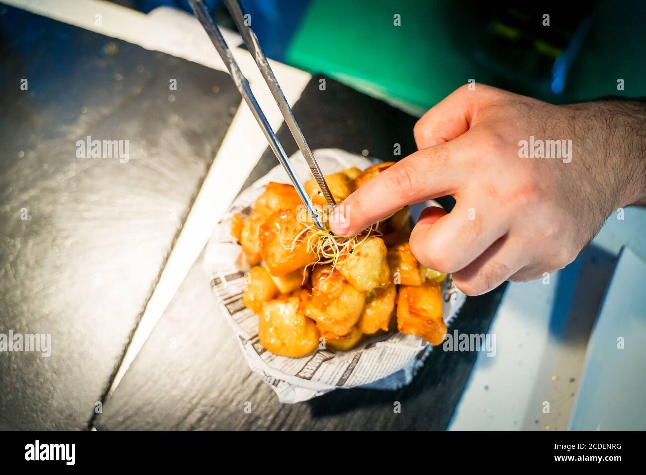 Lo chef prepara patatine fritte, sullo sfondo con un giornale. Preparazione di alimenti gustosi ma nocivi - immagine. Foto Stock