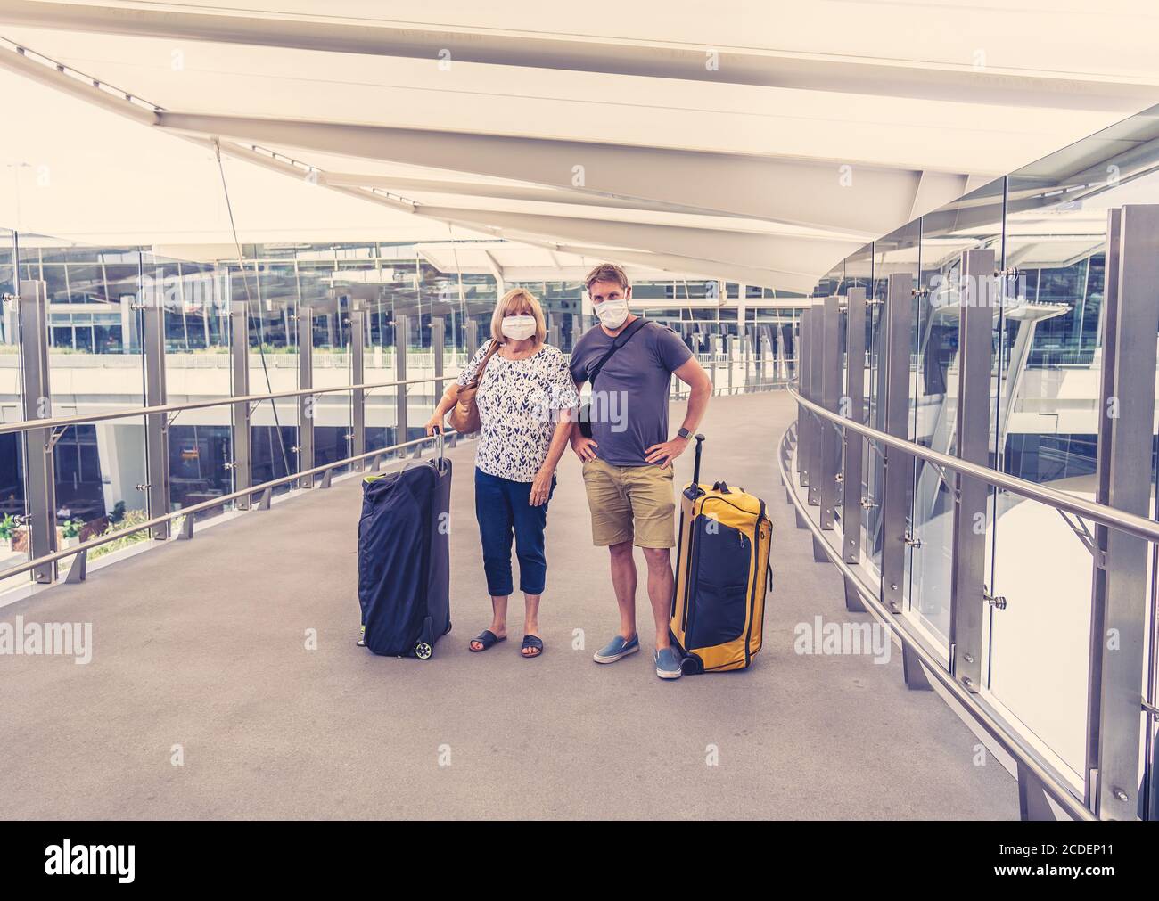 COVID-19 viaggio nella nuova normalità. Figlio e madre anziana con maschera protettiva al aeroporto di ritorno paese di origine preoccupato di coronavirus q Foto Stock