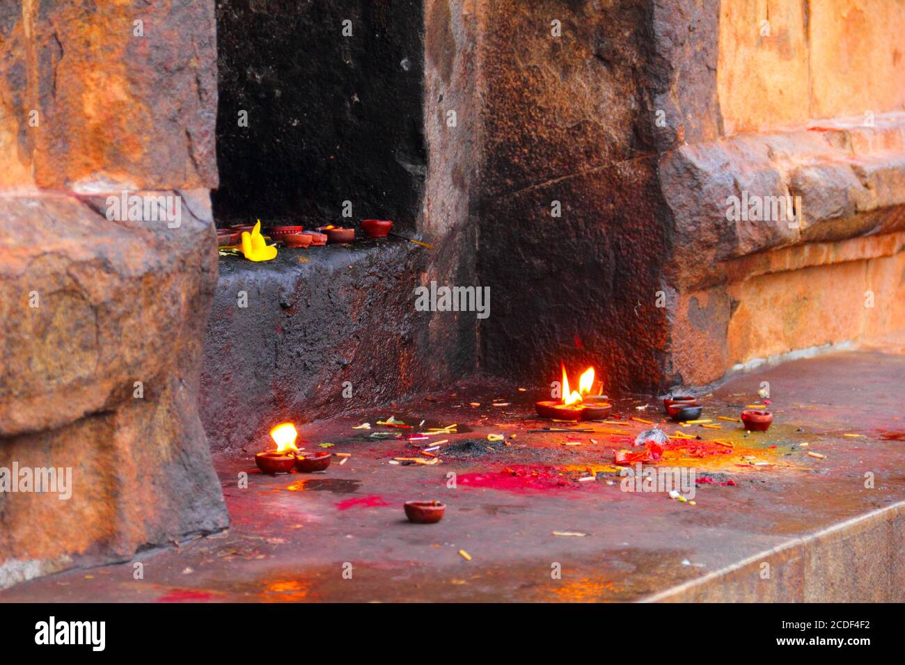 Immagine colorata di pietra santuario indù con candele brucianti, polvere di colore e bastoni di joss nel tempio di Sri Brihadeeswara, Thanjavur (Tanjore), Tamil Nadu, Foto Stock
