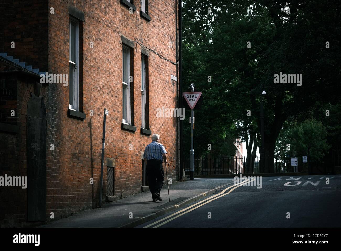 Uomo anziano che cammina con bastone a Preston, Lancashire, Regno Unito. Foto Stock