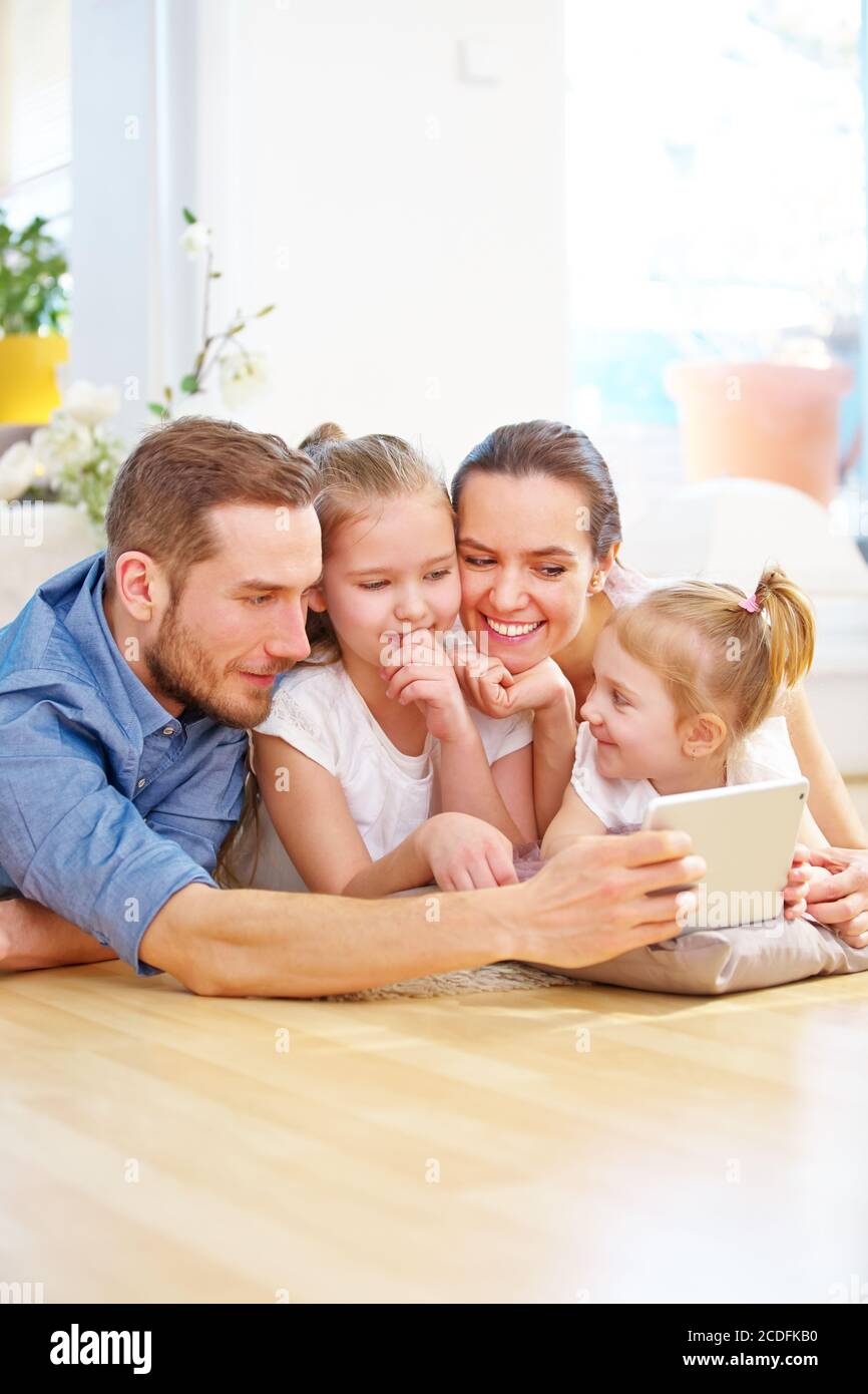 Madre, padre e bambini giocano con il tablet PC a casa Foto Stock