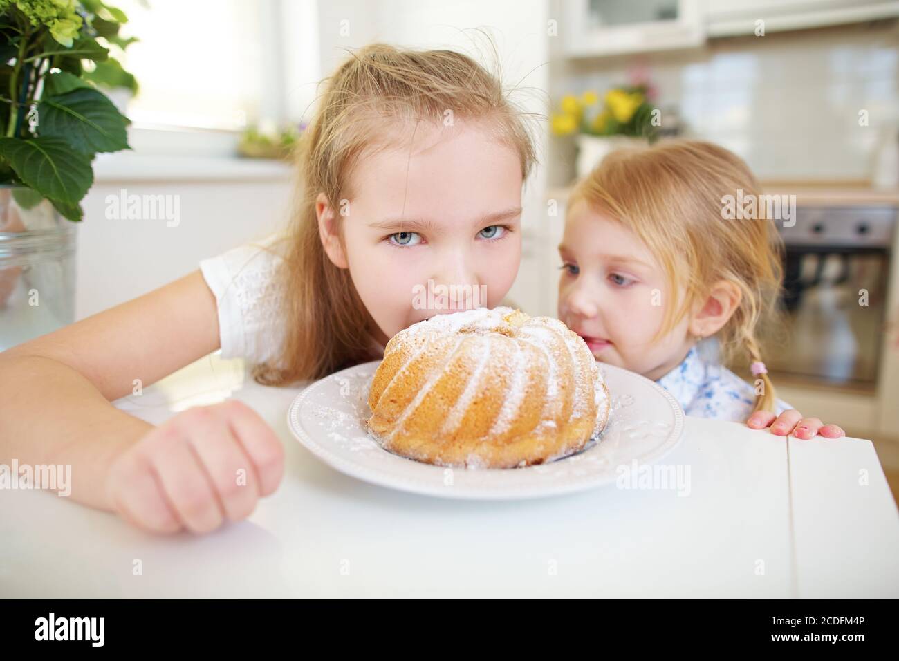 Due bambini si nutrono di snack e di torte in cucina Foto Stock