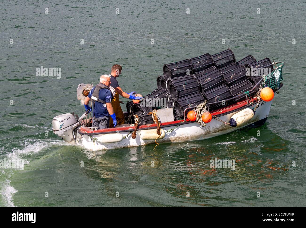 Pescatori di gamberetti che si imbarcano con una barca piena di vasi di gamberetti. Foto Stock