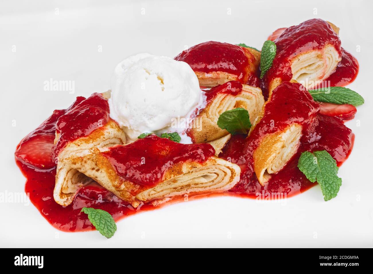 Dessert fatto in casa di frittelle tagliate a pezzetti con scoop di gelato alla vaniglia e foglie di menta isolate su bianco Foto Stock