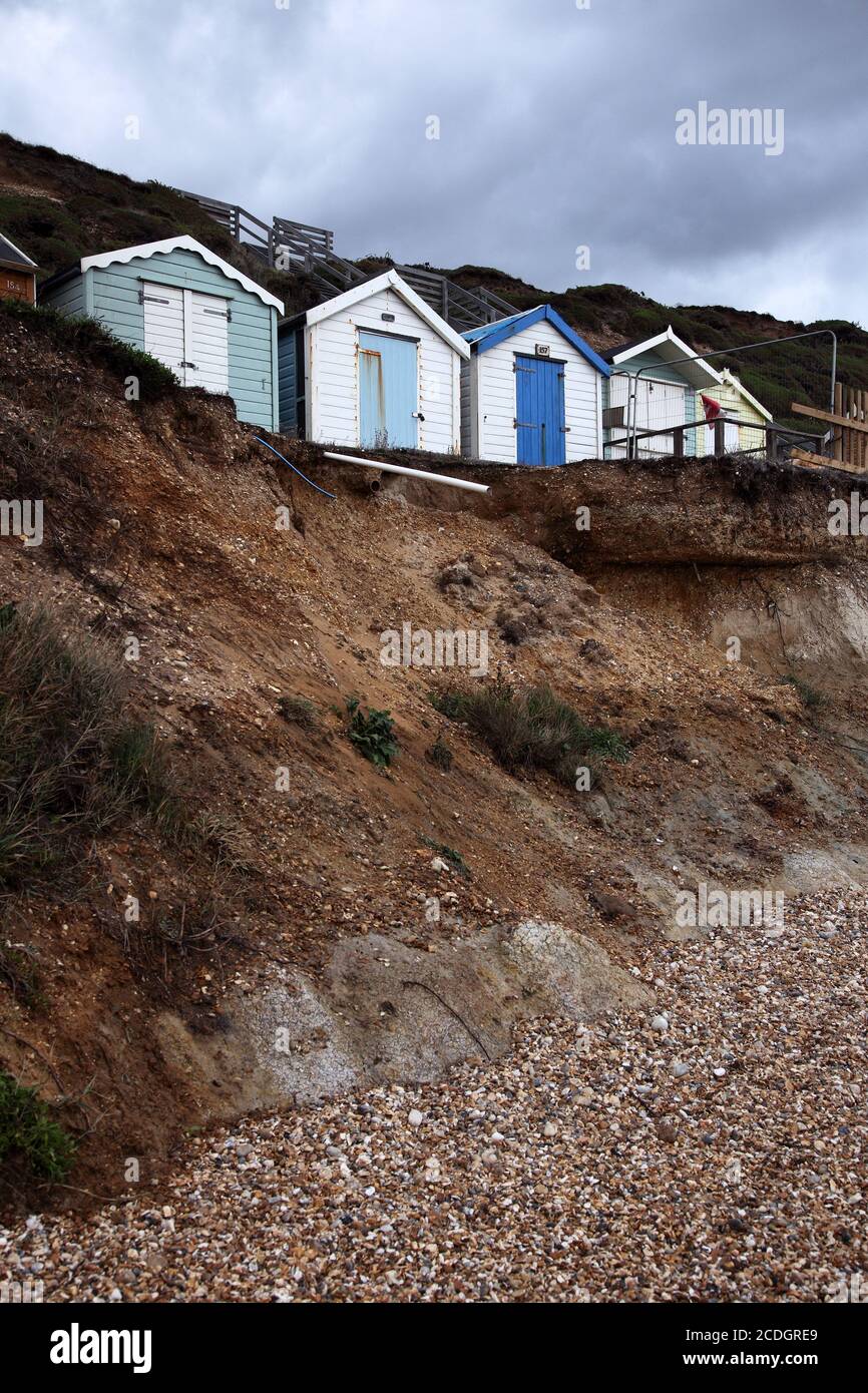 Fila di capanne sulla spiaggia presto per cadere dalla scogliera a causa dell'erosione costiera Foto Stock