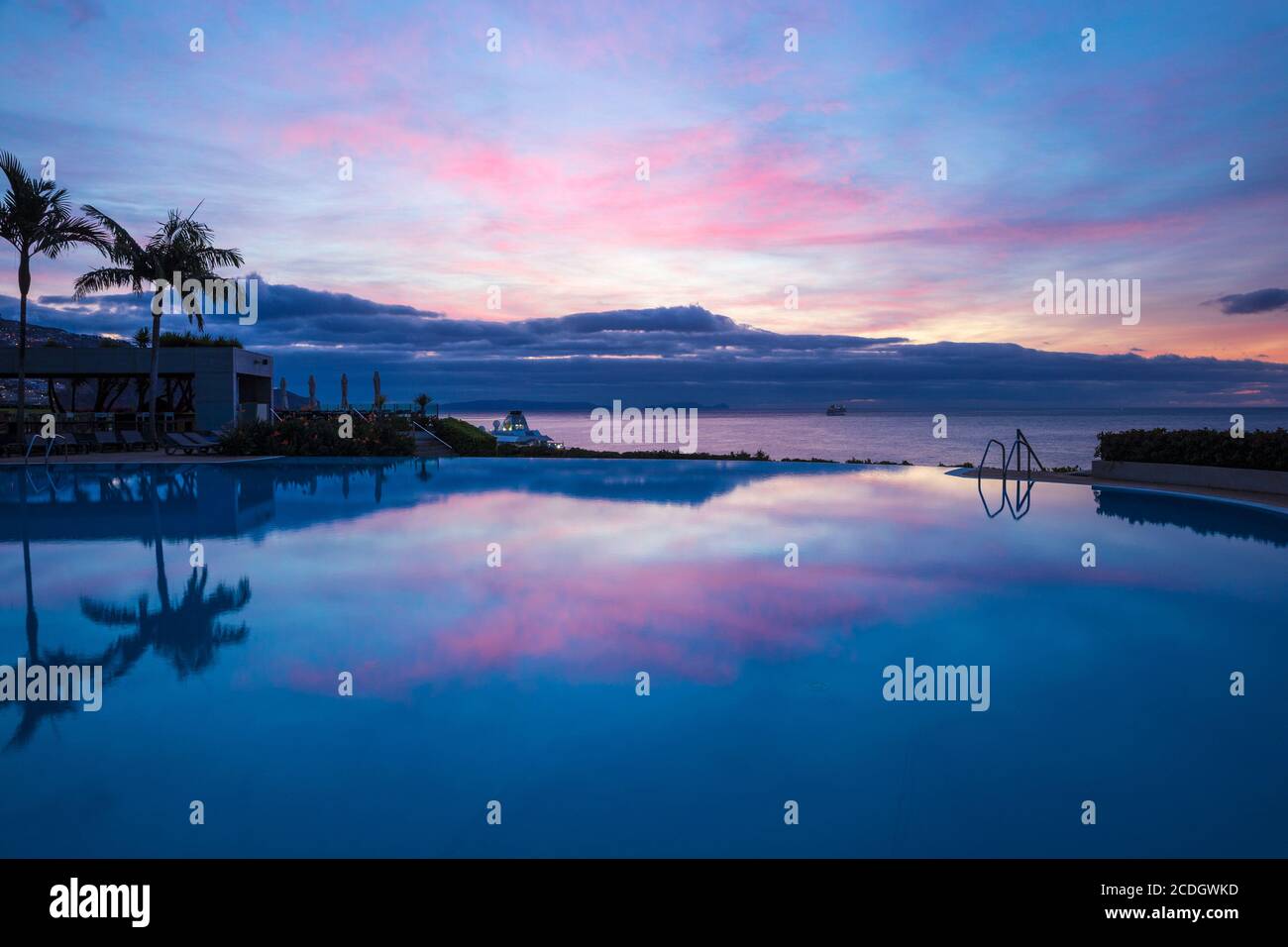 Portogallo, Madeira, Funchal Sunrise, che si riflette nella piscina infinity del Pestana Casino Hotel Foto Stock