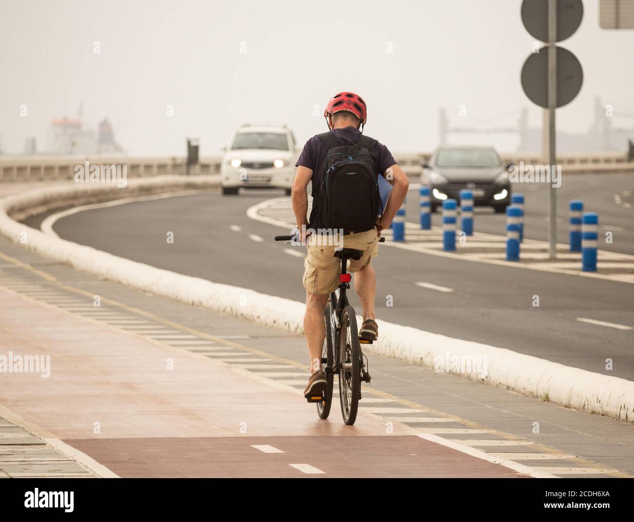 Vista posteriore del ciclista in bicicletta senza mani sulla corsia di scorrimento separata dal traffico. Spagna Foto Stock